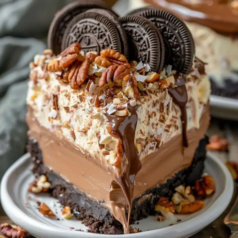 Slice of no-bake German chocolate cheesecake topped with caramel, coconut, and pecans on a white plate