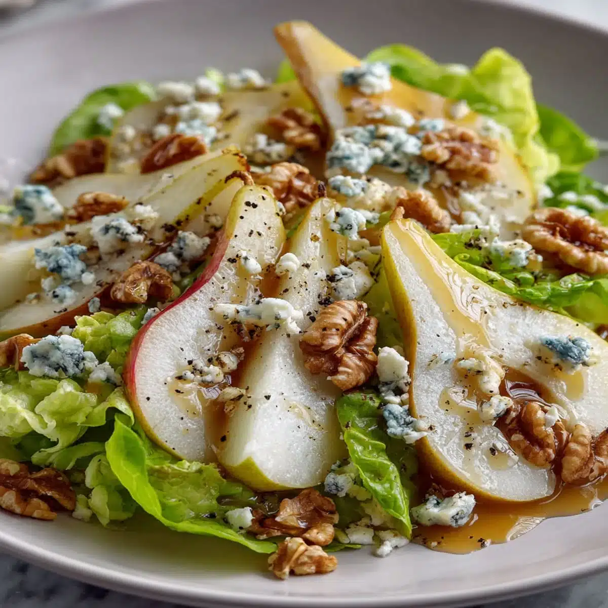 Fresh pear slices with crumbled blue cheese and toasted walnuts on greens