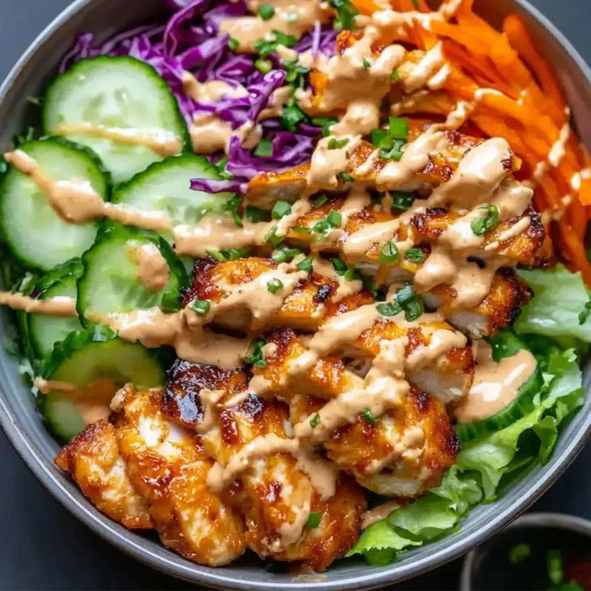 Bang Bang Chicken Bowl with grilled chicken, fresh vegetables, and creamy sauce in a meal prep bowl.