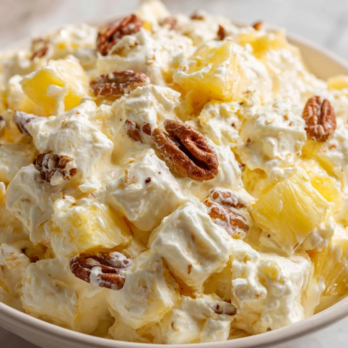 Creamy Cool Whip Pineapple Fluff Recipe 4 Cool Whip Pineapple Fluff dessert served in a glass cup topped with whipped cream, pineapple chunks, and toasted walnuts.