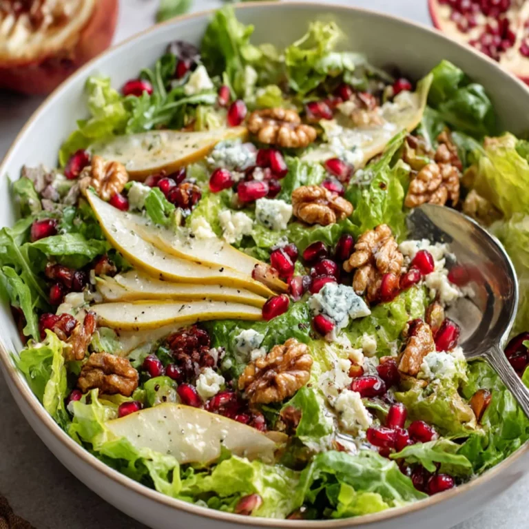 Pear, Pomegranate and Blue Cheese Salad with fresh greens in a white bowl
