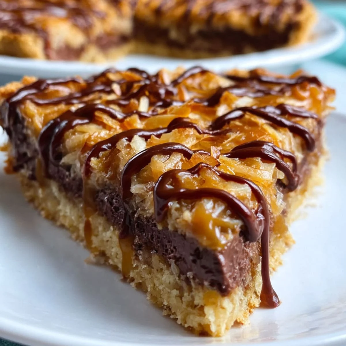 Close-up of a gooey Samoa Pie slice with caramel, coconut, and chocolate layers on a white plate