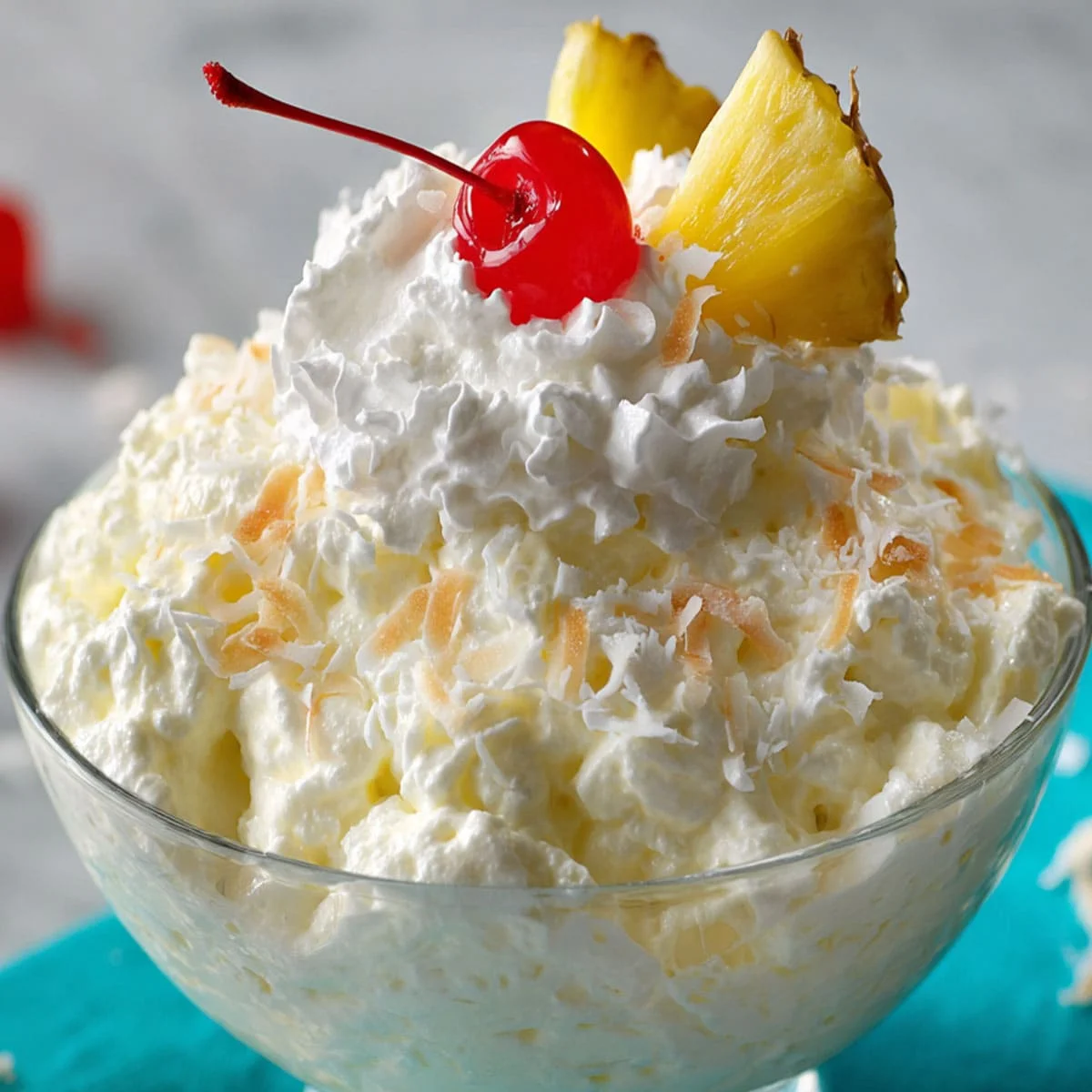 Whipped Pina Colada Fluff topped with toasted coconut, pineapple, and cherry