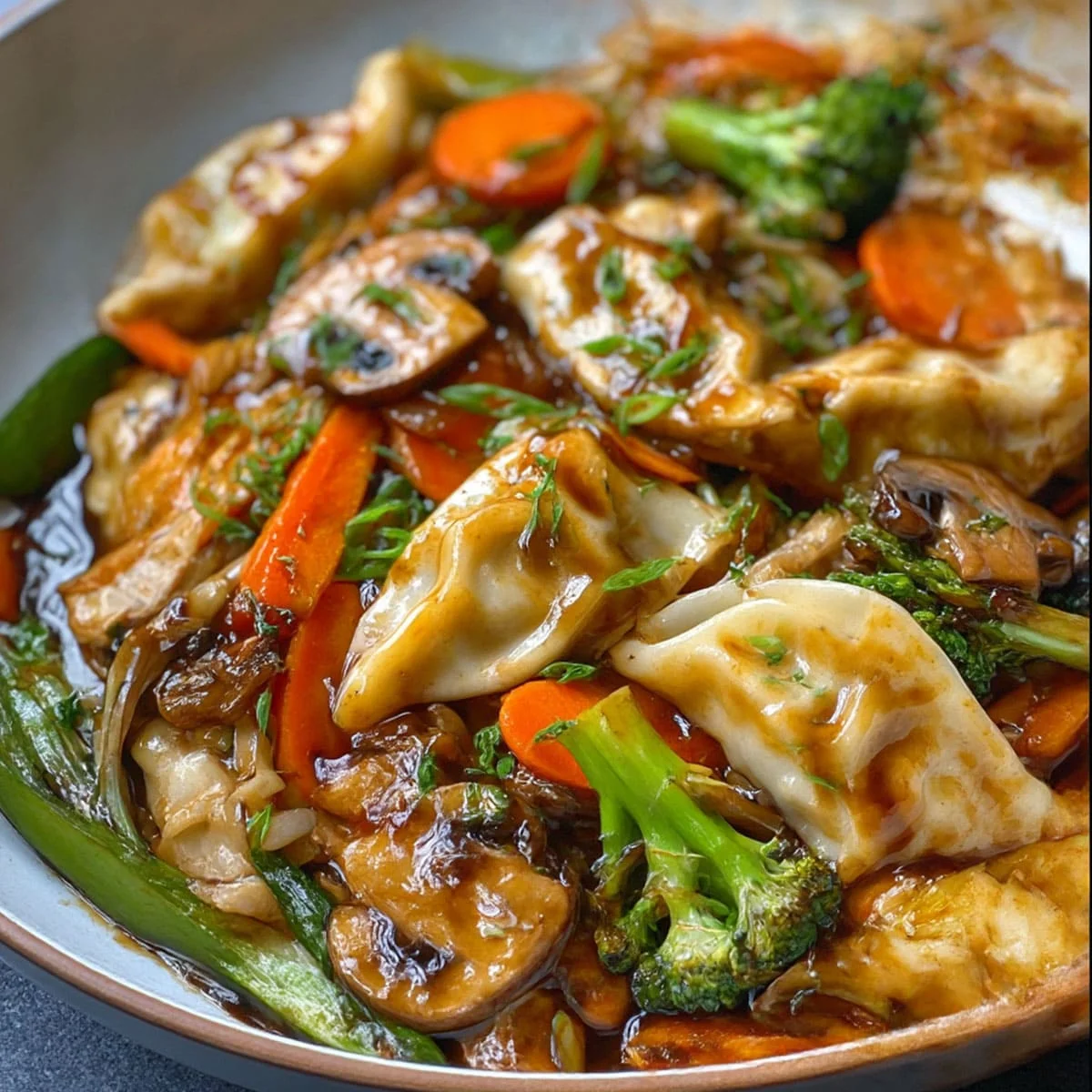Close-up of Potsticker Stir Fry with glossy sauce, carrots, mushrooms, and green onions