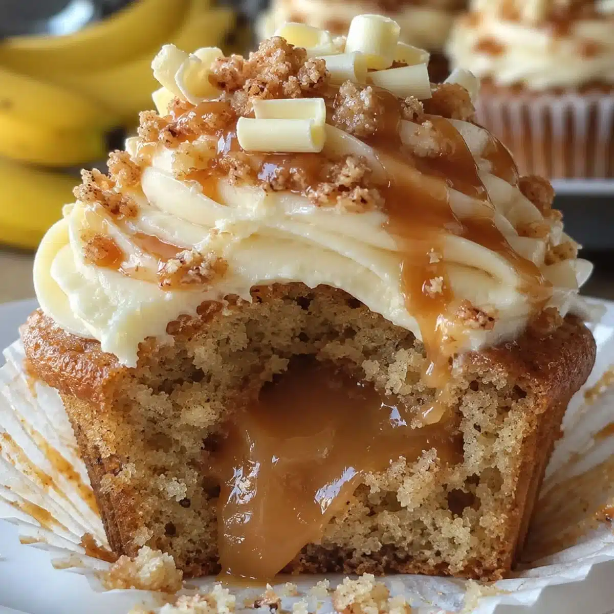 Banana cupcakes with moist banana crumb, creamy frosting, caramel filling, caramel drizzle, and crunchy topping.